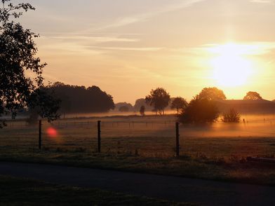Sonnenaufgang über Wiesen und Wäldern.