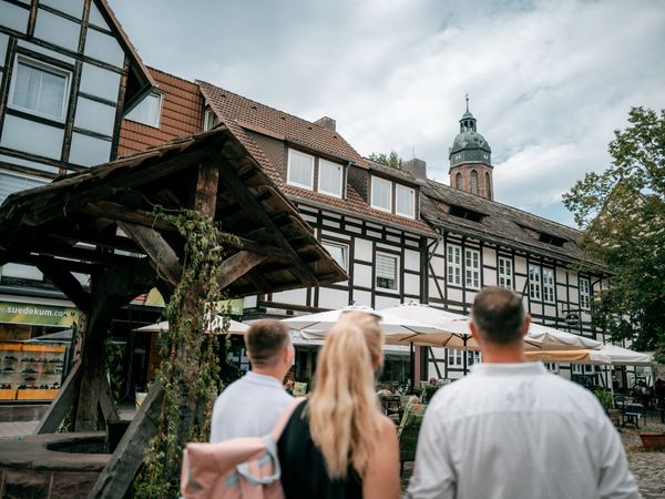 Eine Familie steht neben dem Brunnen auf dem Hallenplan.